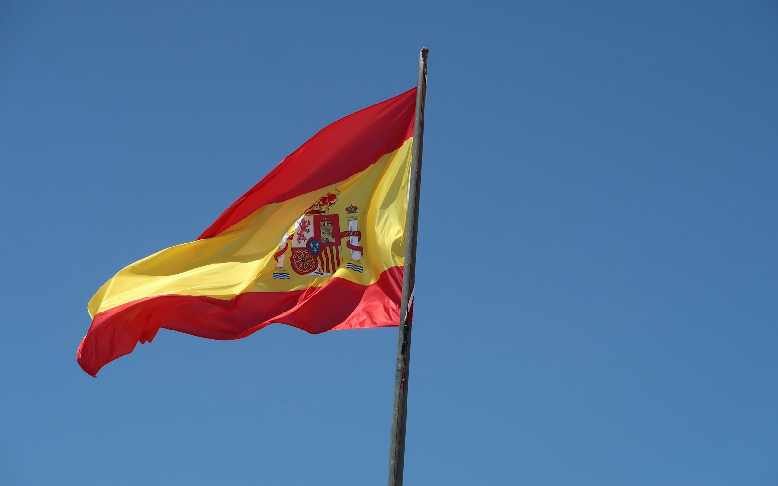 Bandera de España ondeando bajo un cielo azul